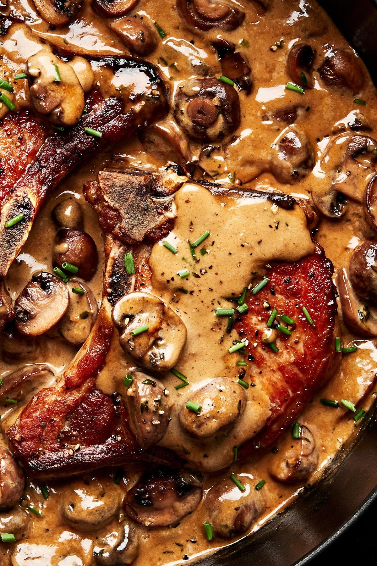pork chops with mushroom cream sauce in a skillet with fresh thyme