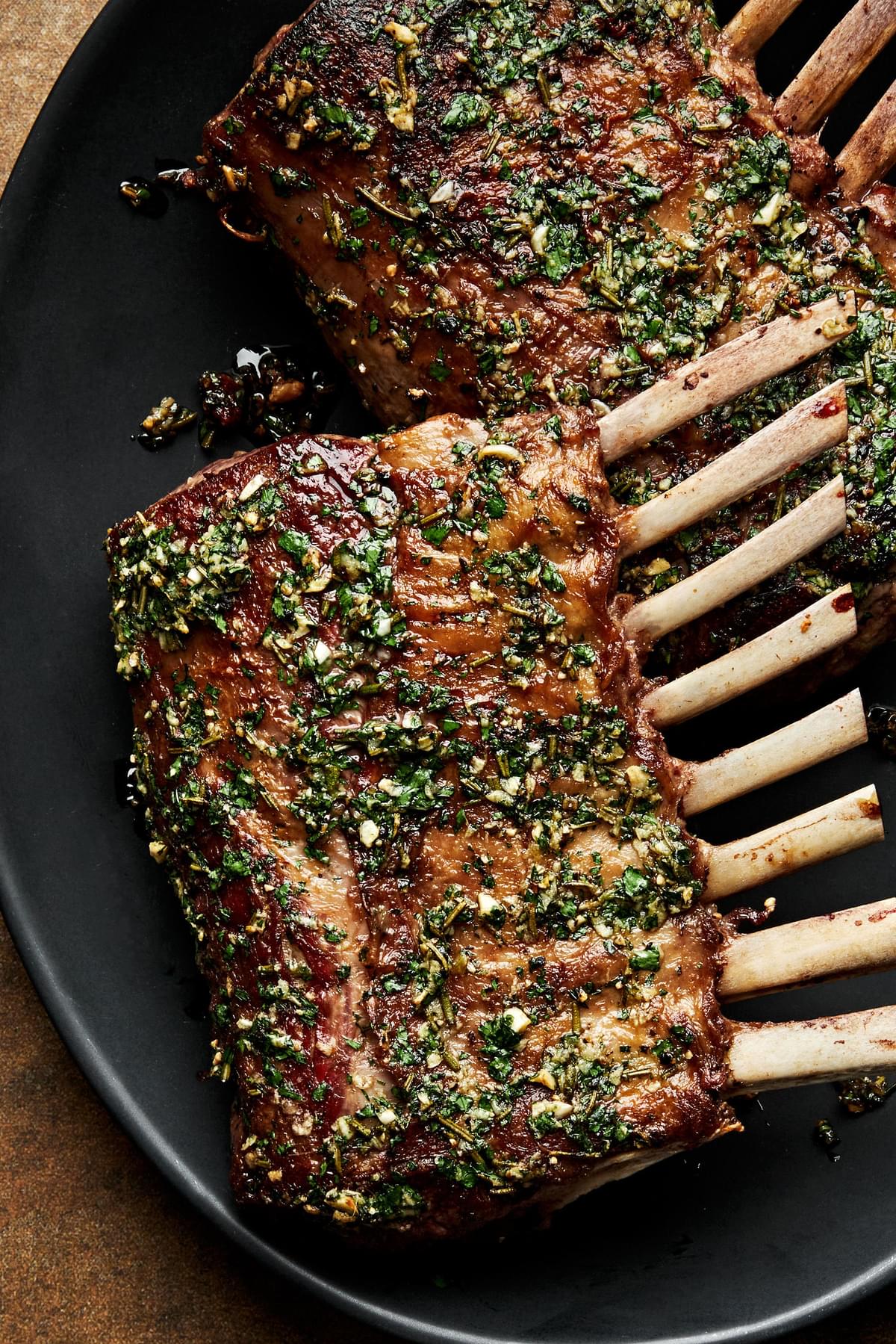 a roasted rack of lamb topped with mint sauce on a serving platter