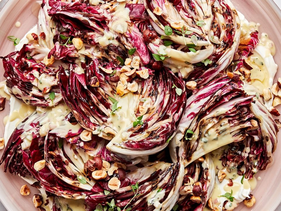 Radicchio salad with Crème Fraîche Vinaigrette sprinkled with toasted hazelnuts, thyme and drizzled with honey on a plate