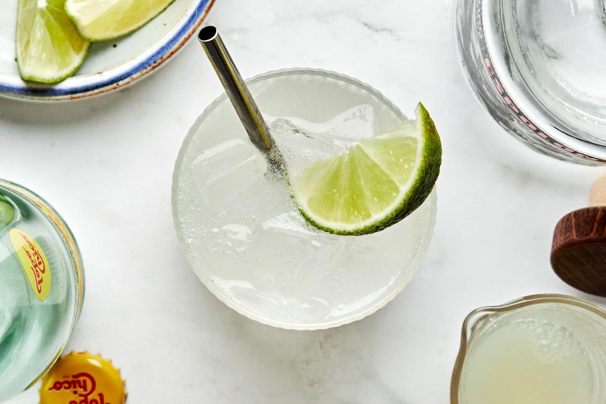 a glass of ranch water made with tequila, lime juice and sparkling mineral water garnished with a lime wedge