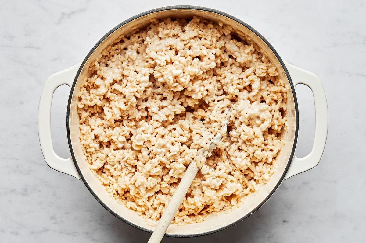 homemade rice crispy treats being stirred in a large pot with a wooden spoon
