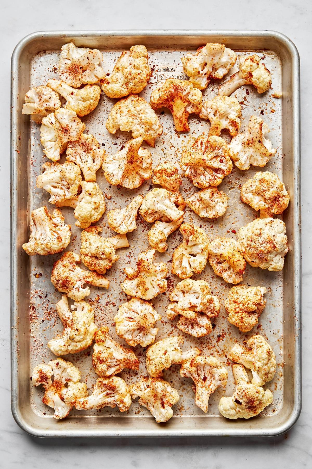 cauliflower florets tossed with olive oil, salt, garlic powder, smoked paprika and red pepper flakes on a baking sheet