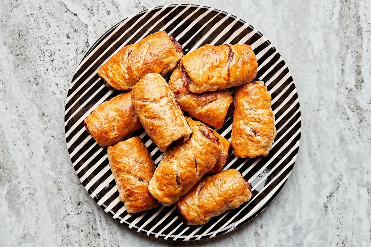 ten sausage rolls shown on a black and white striped plate