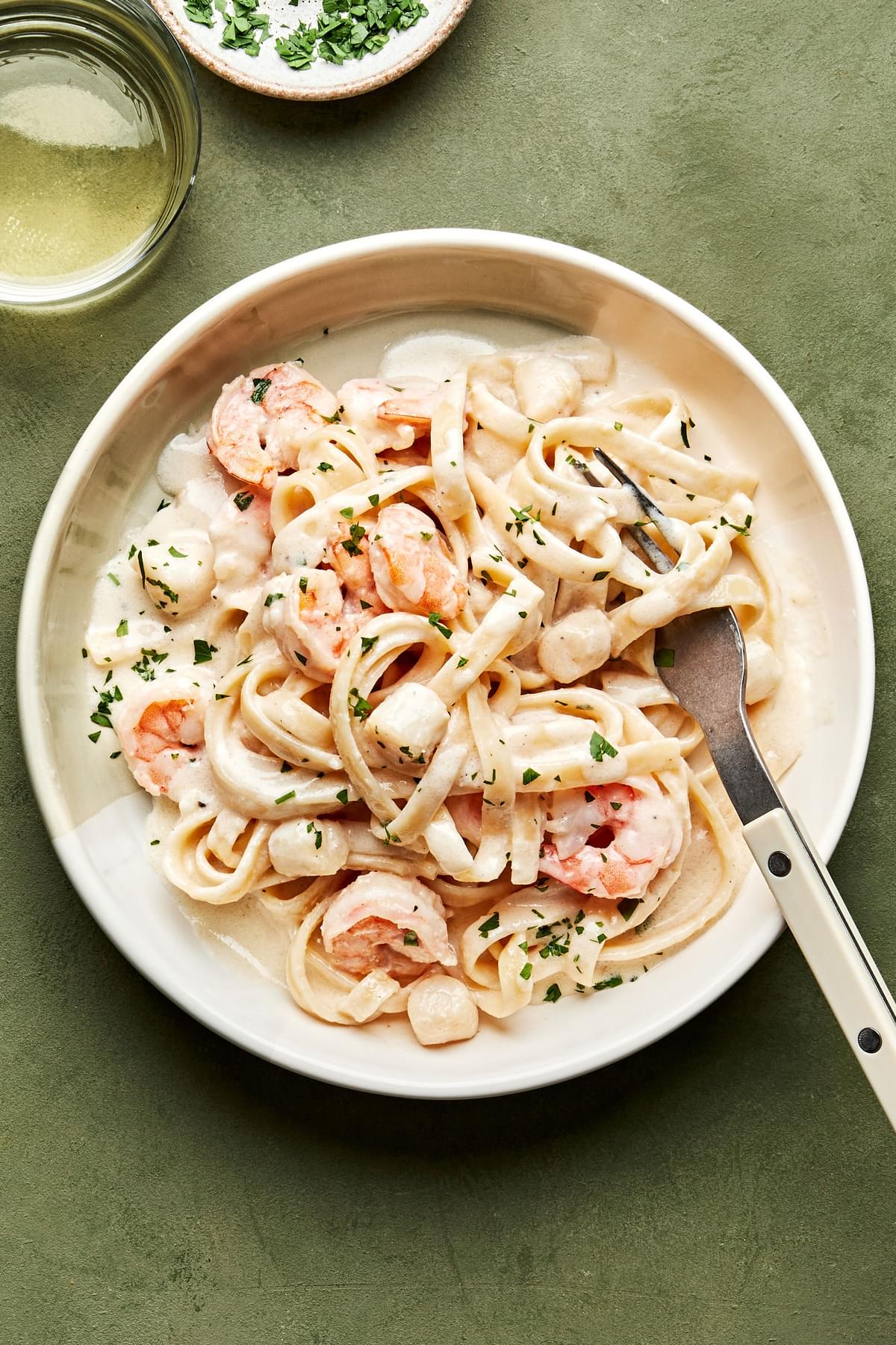a bowl of homemade seafood fettuccine alfredo made with shrimp and scallops, sprinkled with parsley