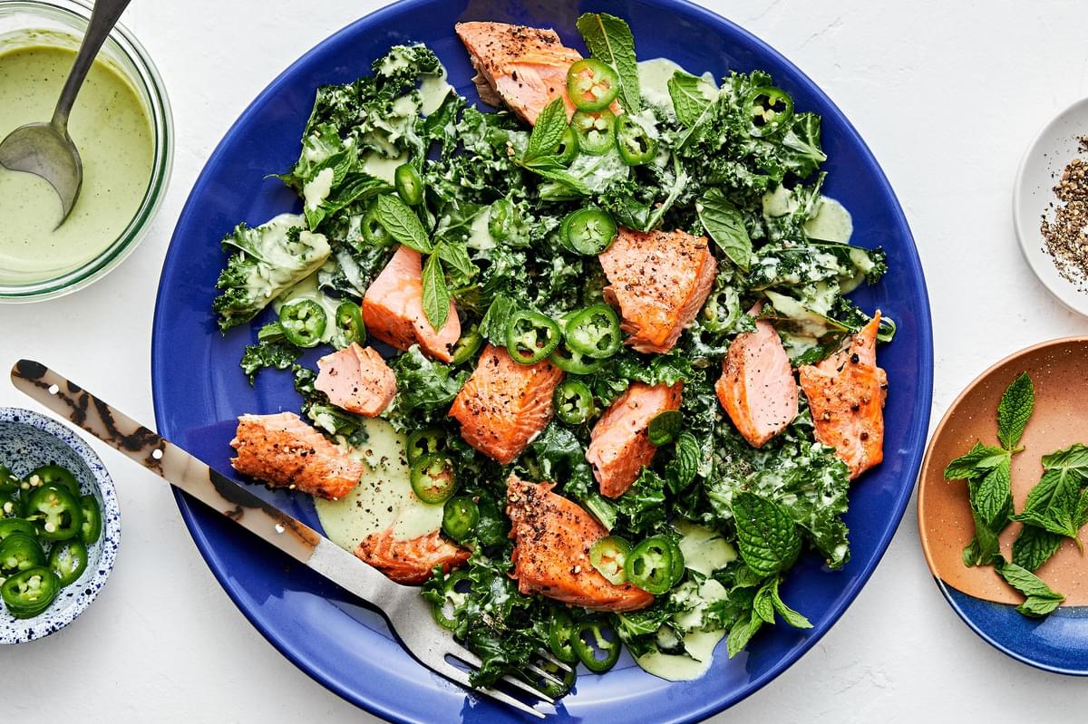 Serrano Mint Kale Salad with Salmon garnished with serrano peppers and parmesan in a serving bowl