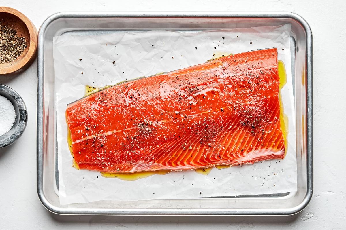 salmon filet on a parchment lined baking sheet brushed with olive oil and seasoned with salt and pepper