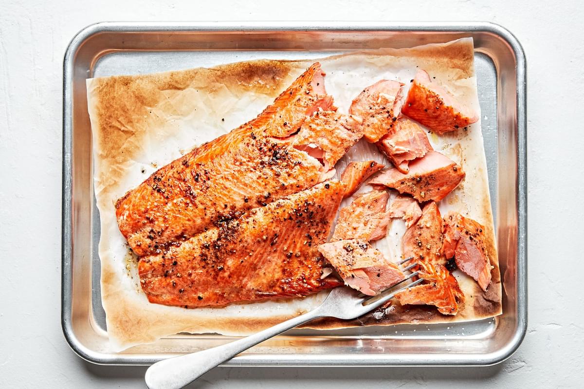 broiled salmon on a parchment lined baking sheet brushed with olive oil and seasoned with salt and pepper