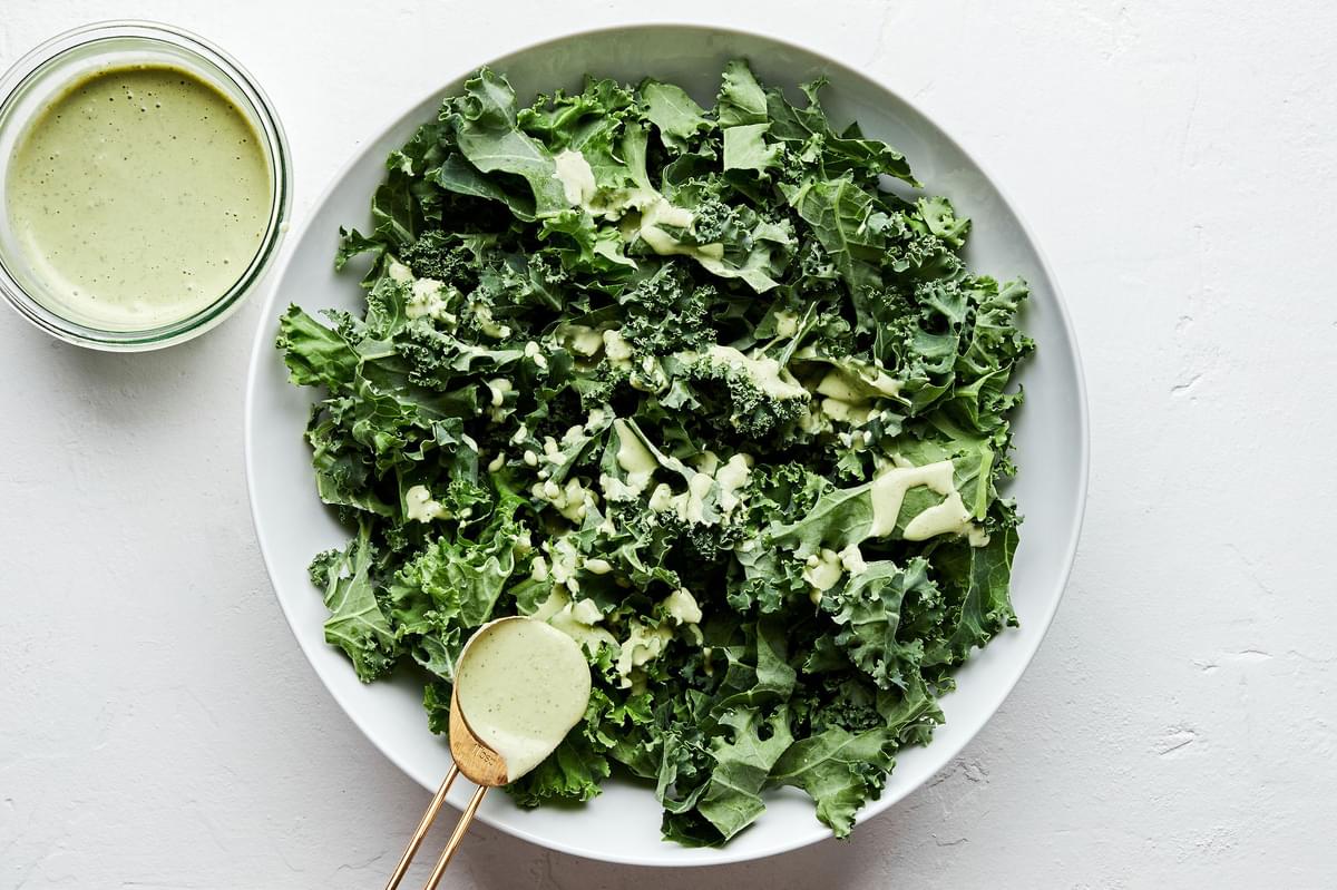 kale being drizzled with serrano mint salad dressing