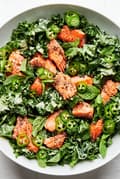 Serrano Mint Kale Salad with Salmon garnished with serrano peppers and parmesan in a serving bowl