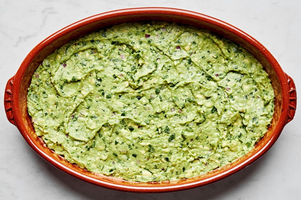 refried beans, sour cream and guacamole layered in a serving bowl