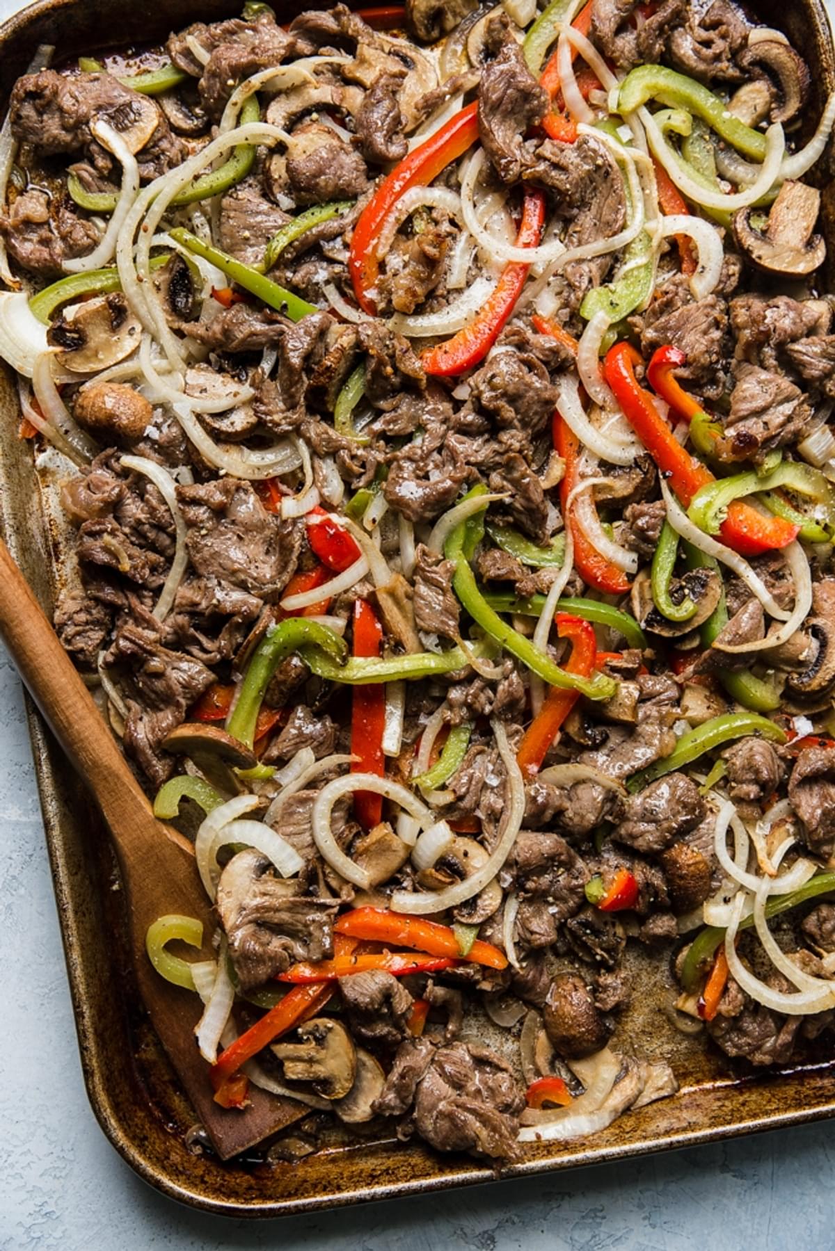 thinly sliced steak bell peppers and onions cooked on a sheet pan for Philly Cheese steak