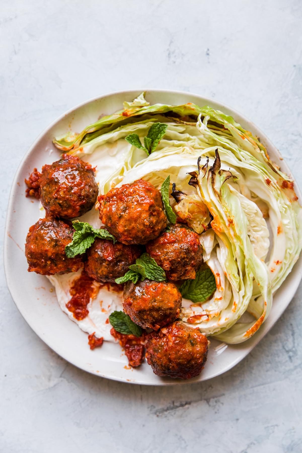 Sheet pan Meatballs with Cabbage and Harissa on a plate served with Greek yogurt