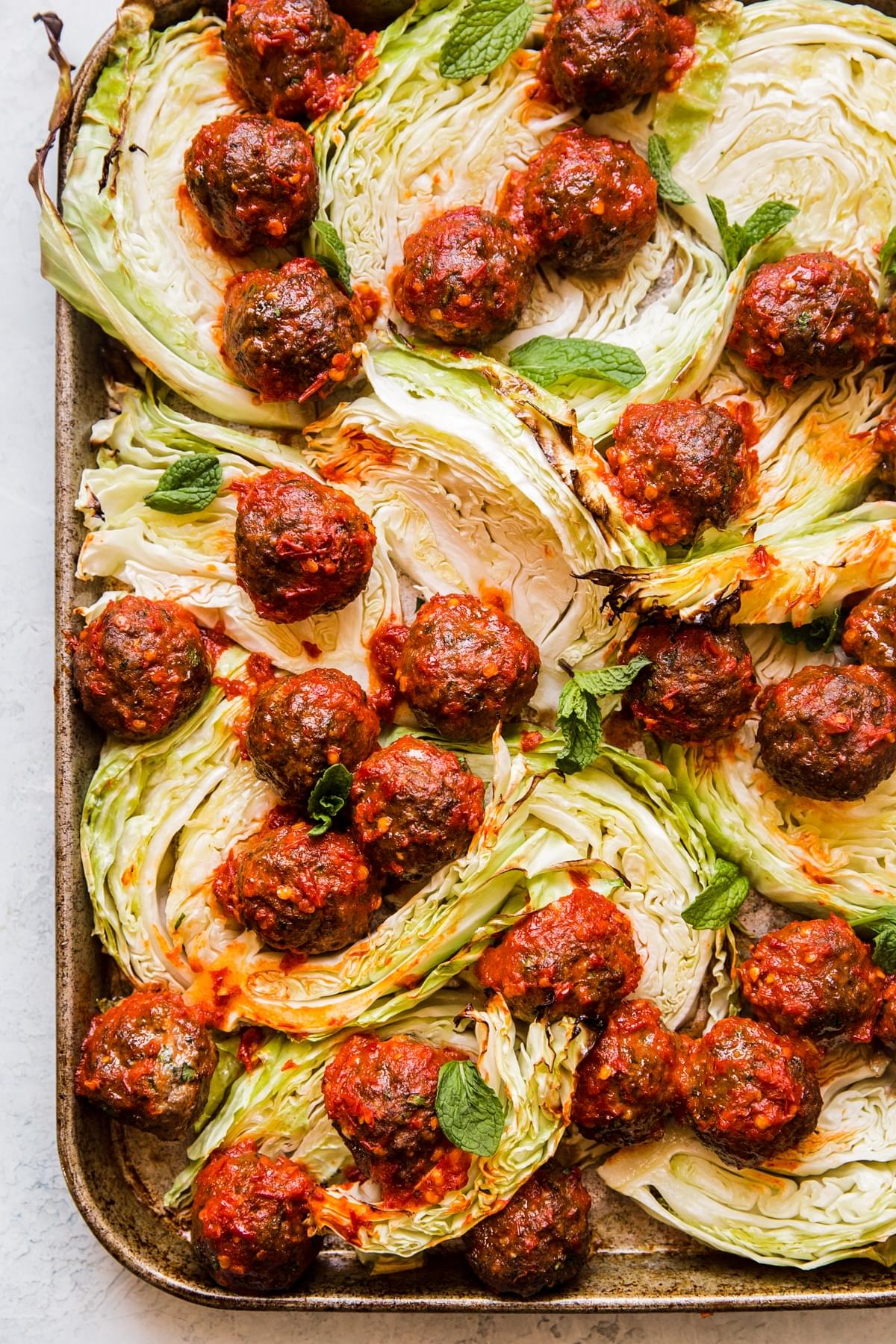 meatballs with cabbage and harissa on a sheet pan