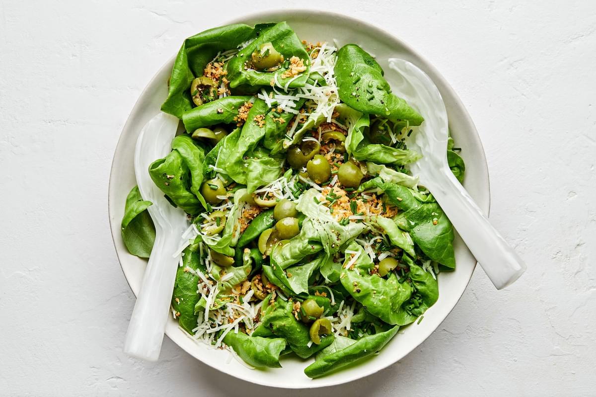 a simple butter lettuce salad with apple cider vinaigrette, olives, breadcrumbs, chives, manchego cheese and ground pepper