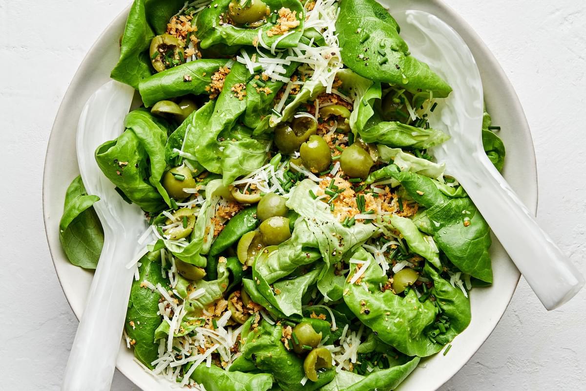 a simple butter lettuce salad with apple cider vinaigrette, olives, breadcrumbs, chives, manchego cheese and ground pepper