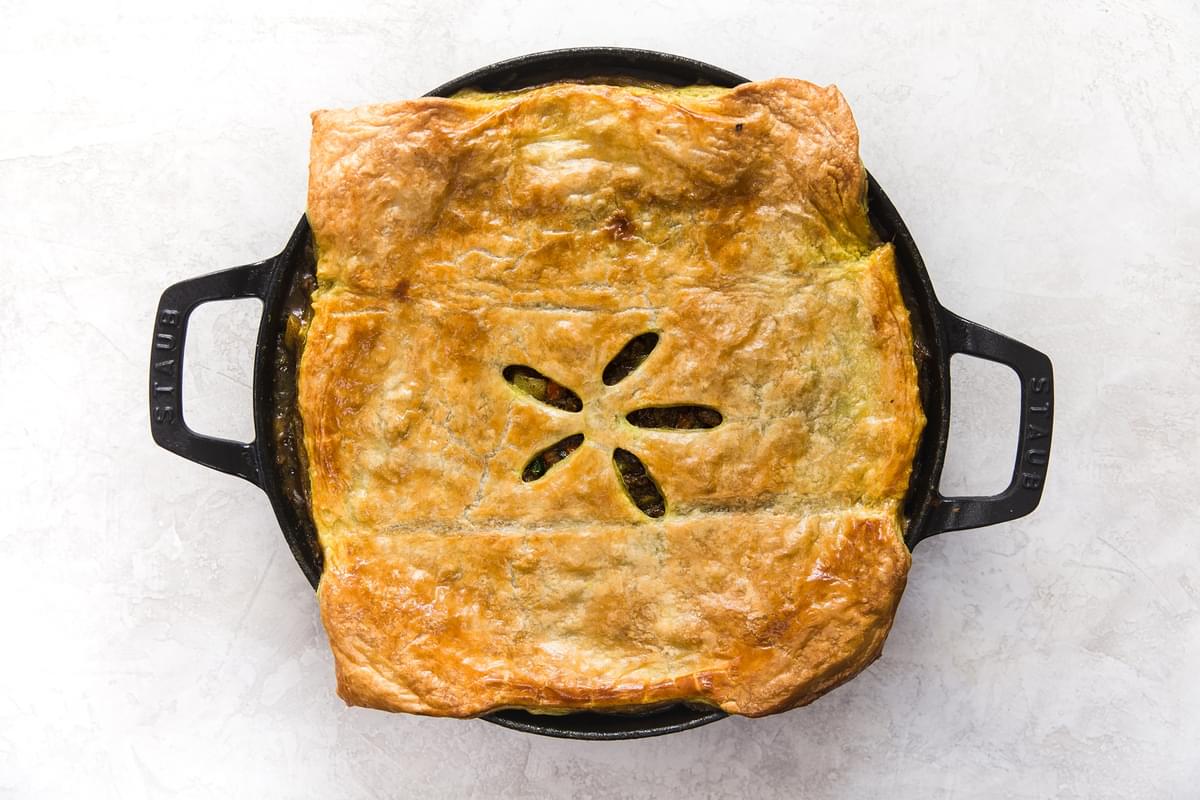 golden brown puff pastry over a lamb pot pie in a large skillet