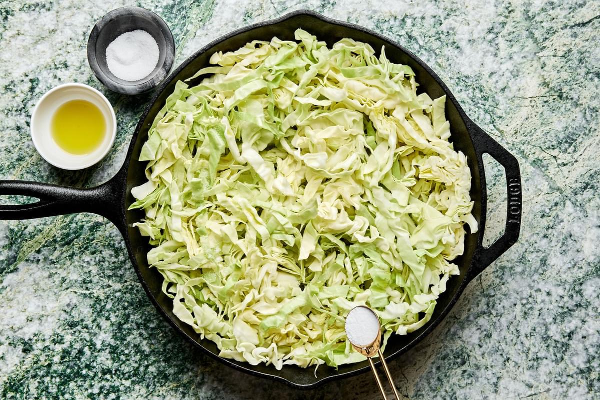 shredded cabbage tossed with olive oil and seasoned with salt in a cast iron skillet