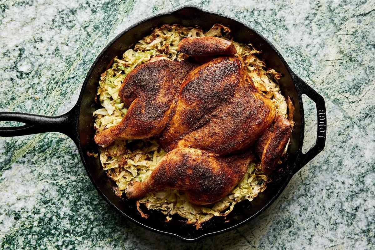 a roasted spatchcocked seasoned with taco seasoning on top of cabbage in a skillet