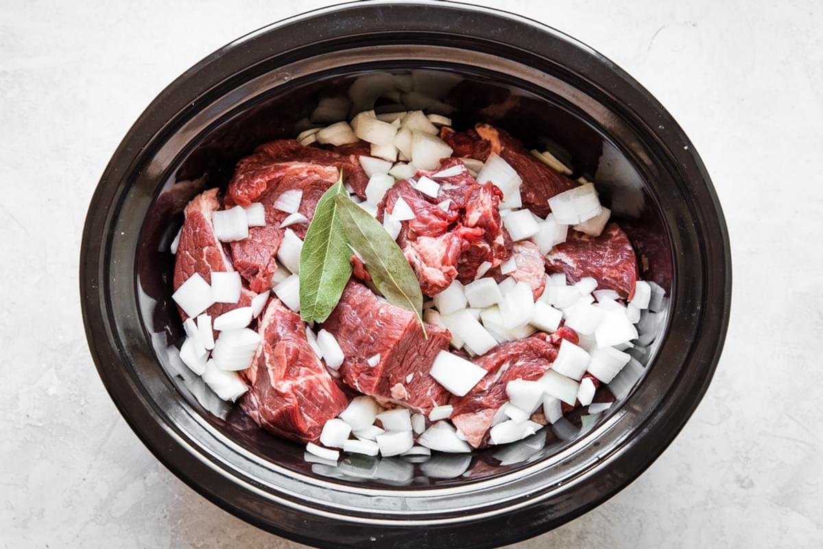 beef onions and bay leaves in a crockpot for Slow Cooker Barbacoa Beef