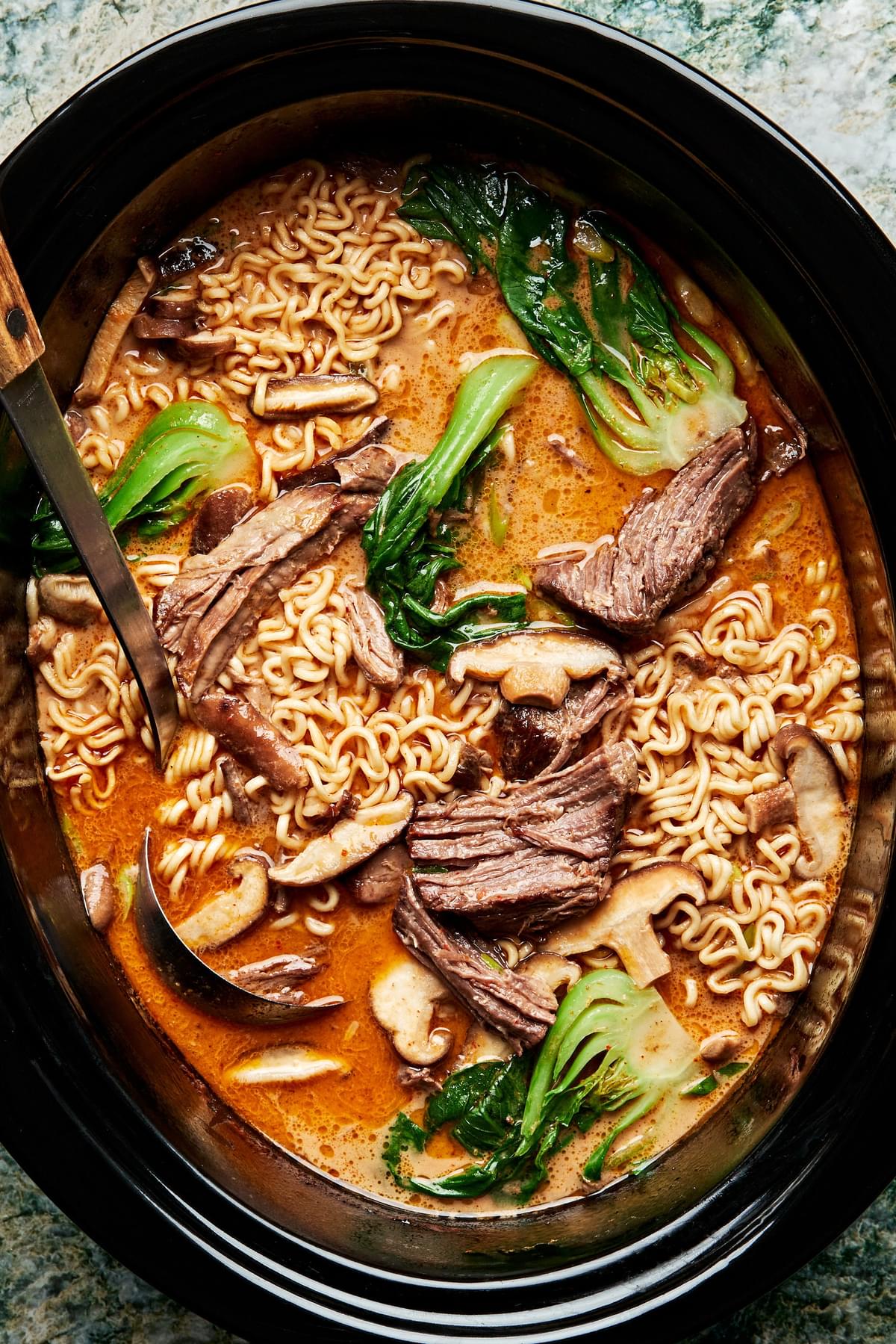 Slow Cooker Curry Beef Ramen made with beef, ramen, mushrooms and bok choy in a slow cooker with a ladle