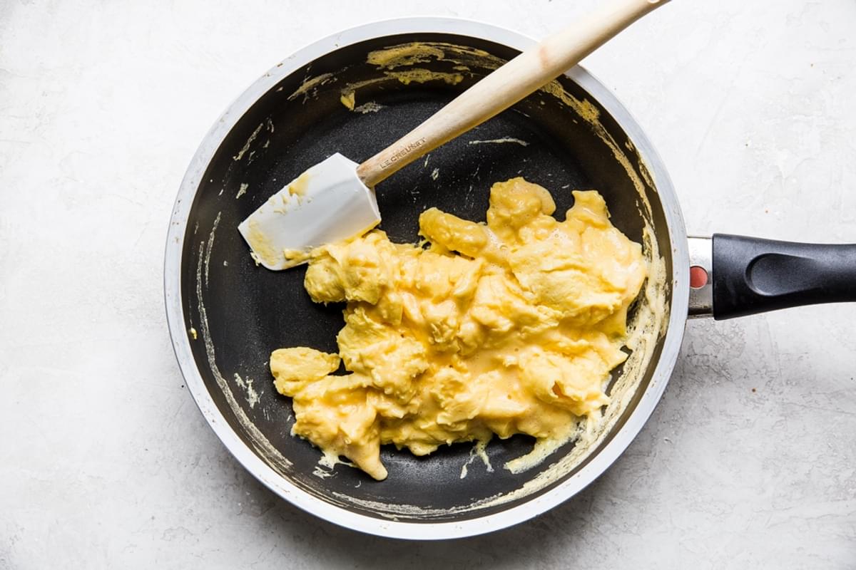 soft scrambled eggs in a frying pan with a rubber spatula