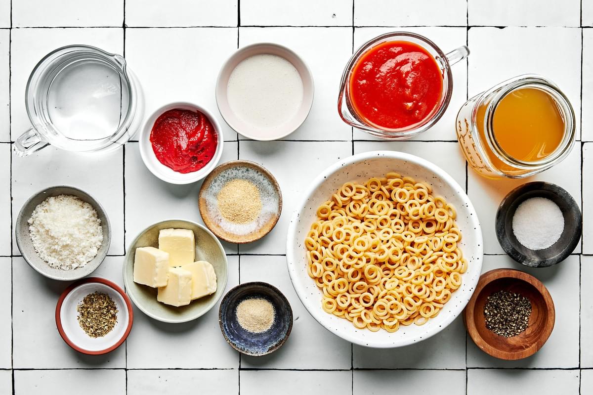 pasta, tomato paste, butter, spices, tomato sauce, chicken stock, heavy cream and Parmesan in prep bowls to make spaghettios