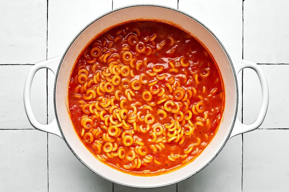 tomato paste, butter, spices, tomato sauce, chicken stock and pasta noodles in a pot