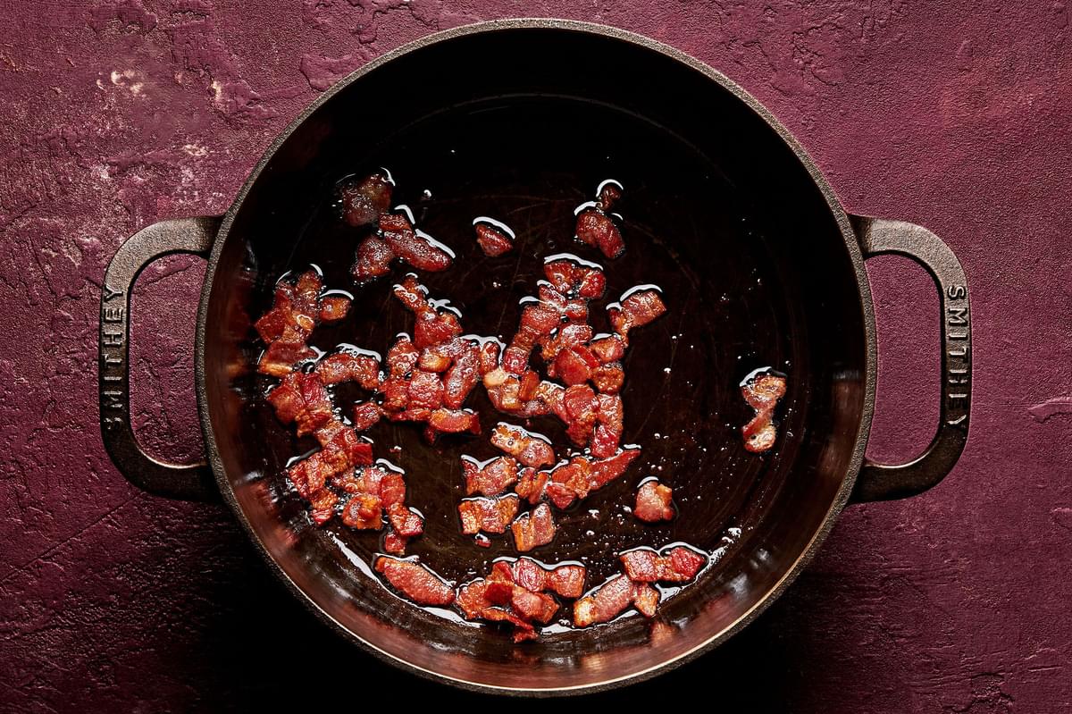 chopped bacon being cooked in a large soup pot