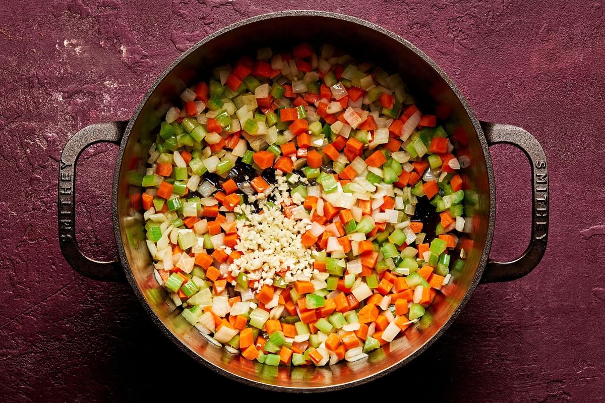 diced onion, celery and carrots being cooked in bacon fat in a large soup pot