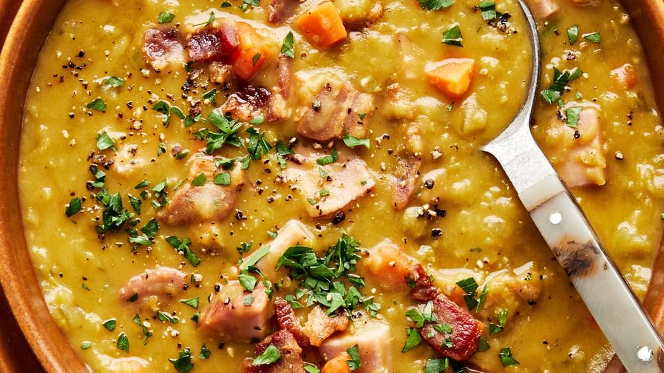 a bowl of homemade split pea soup with ham and bacon sprinkled with fresh parsley