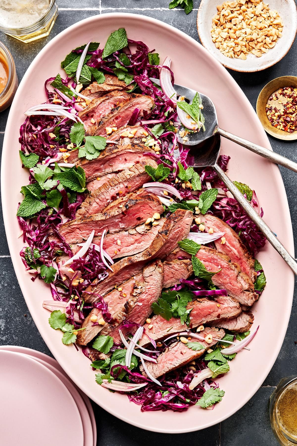 steak salad with thai dressing on a serving platter made with red cabbage, mint, cilantro, shallots and roasted peanuts