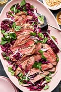 steak salad with thai dressing on a serving platter made with red cabbage, mint, cilantro, shallots and roasted peanuts