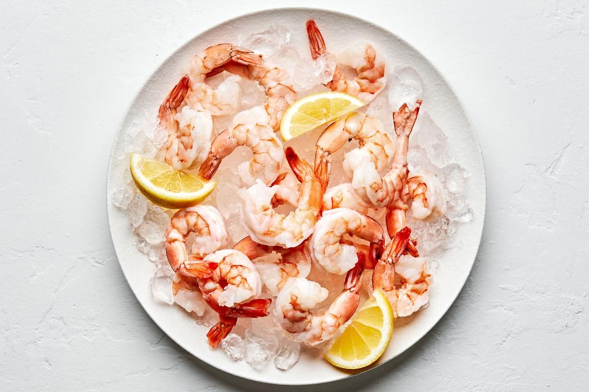 Steamed shrimp on top of ice on a serving platter garnished with lemon wedges