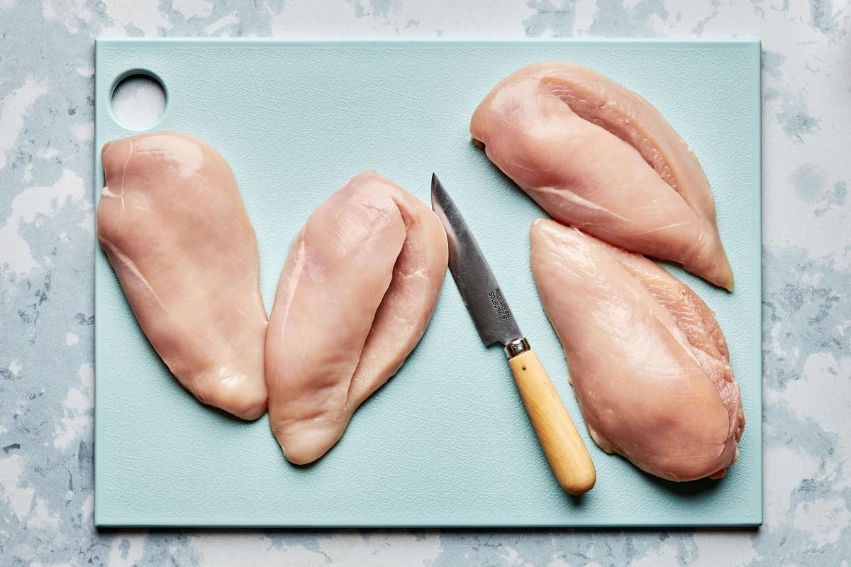 chicken breast sliced in half to create a pocket sitting on a cutting board