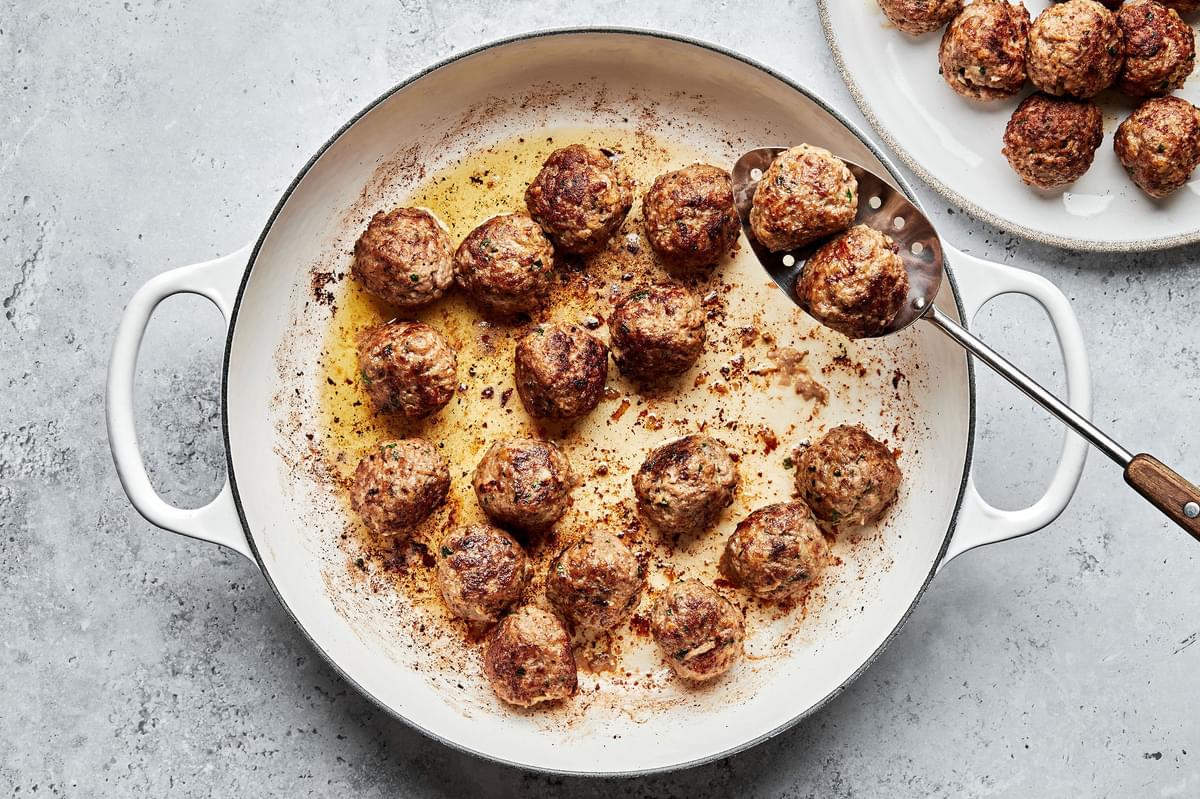 meatballs made with beef and pork being fried in a skillet