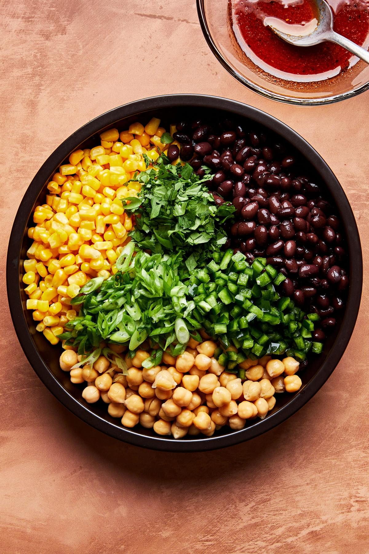 corn, black beans, chickpeas, poblano peppers and cilantro in a large bowl