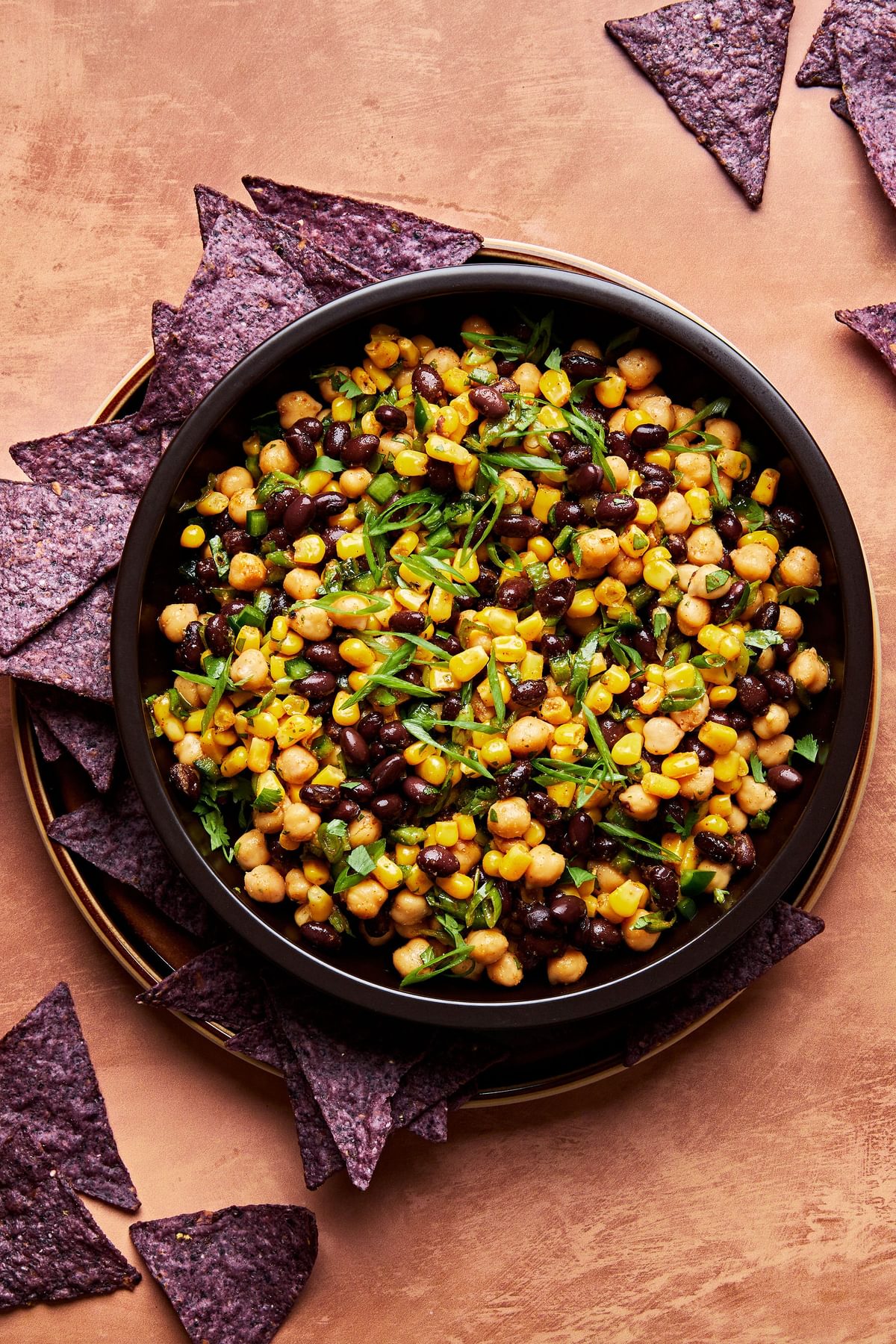 homemade Sweet and Smoky Bean and Corn Salsa in a serving bowl surrounded by tortilla chips for dipping
