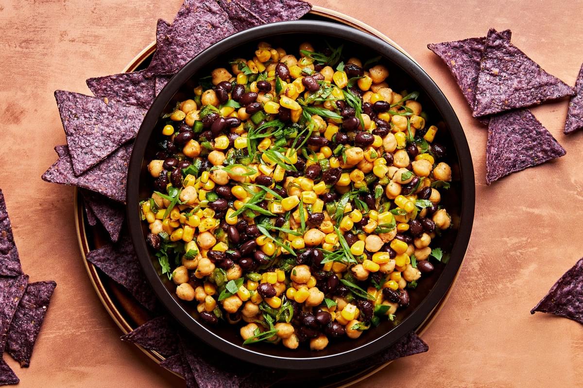 homemade Sweet and Smoky Bean and Corn Salsa in a serving bowl surrounded by tortilla chips for dipping