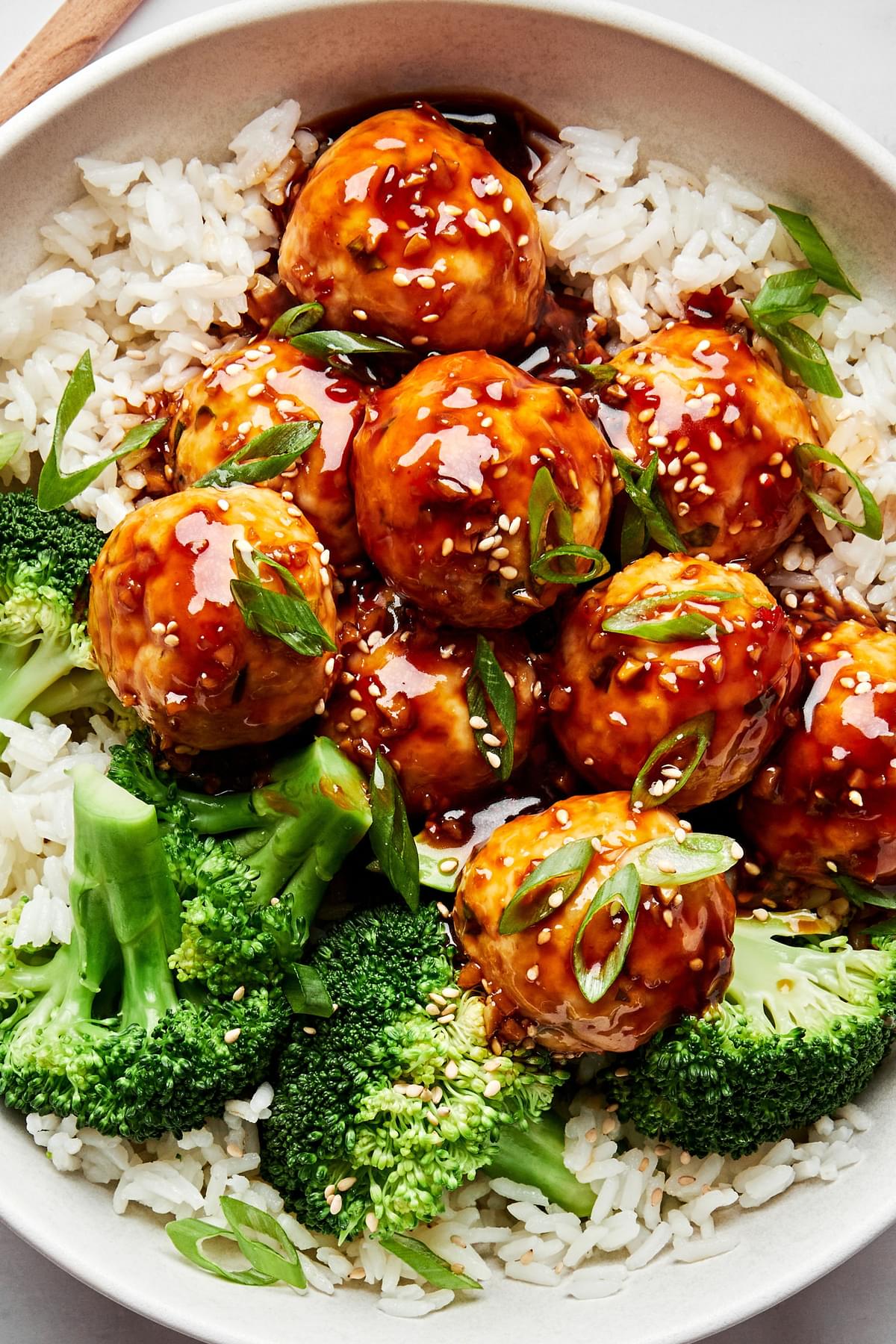 a bowl of homemade teriyaki meatballs served on top of white rice with steamed broccoli