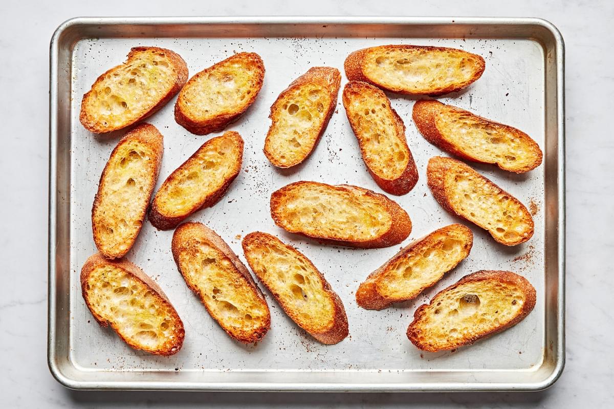 toasted sliced bread brushed with olive oil and sprinkled with garlic powder on a baking sheet