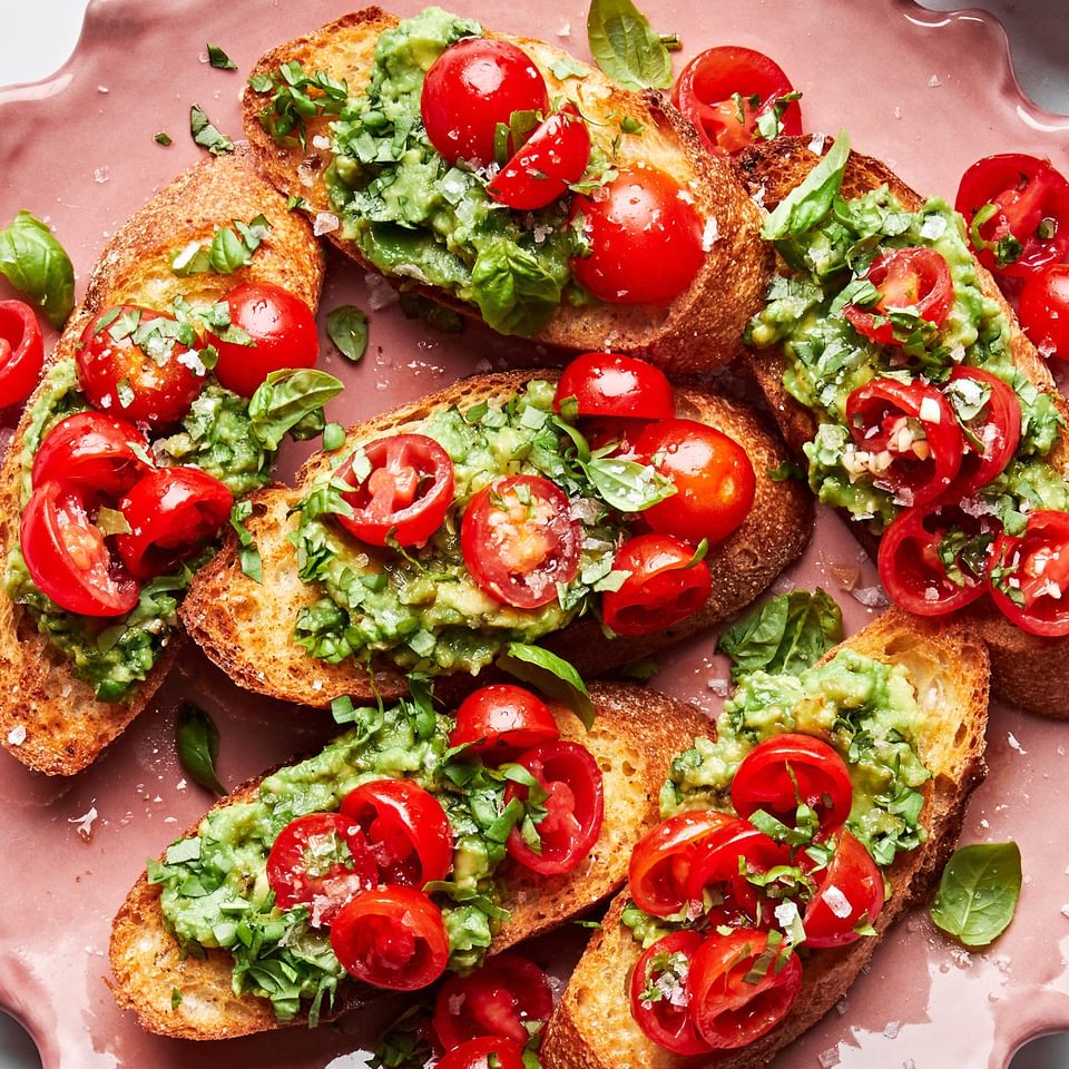 tomato and avocado bruschetta served on crusted garlic bread on a serving platter