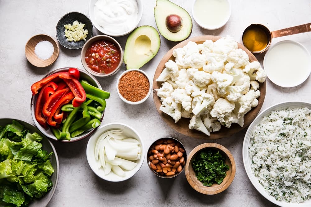 ingredients for vegetarian burrito bowls cilantro rice, cauliflower, avocado, lettuce, taco seasoning, salsa, beans