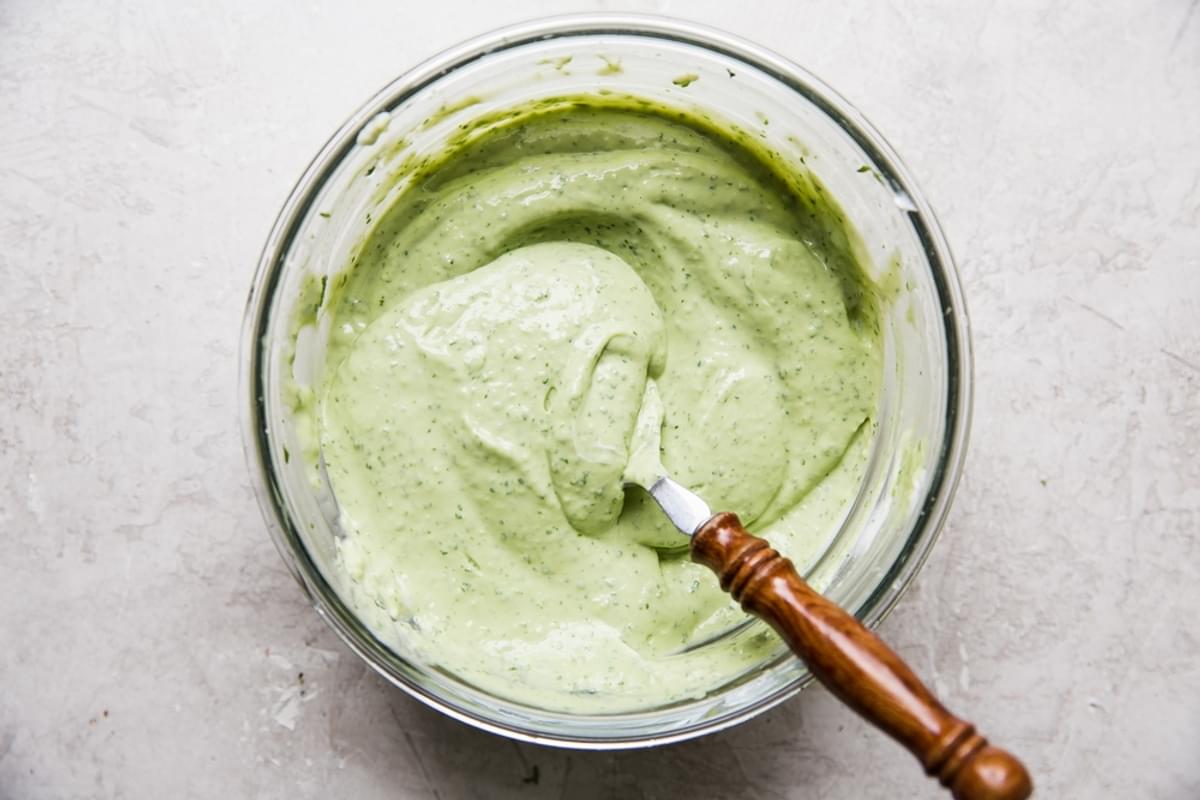 Avocado crema in a small glass bowl with a spoon