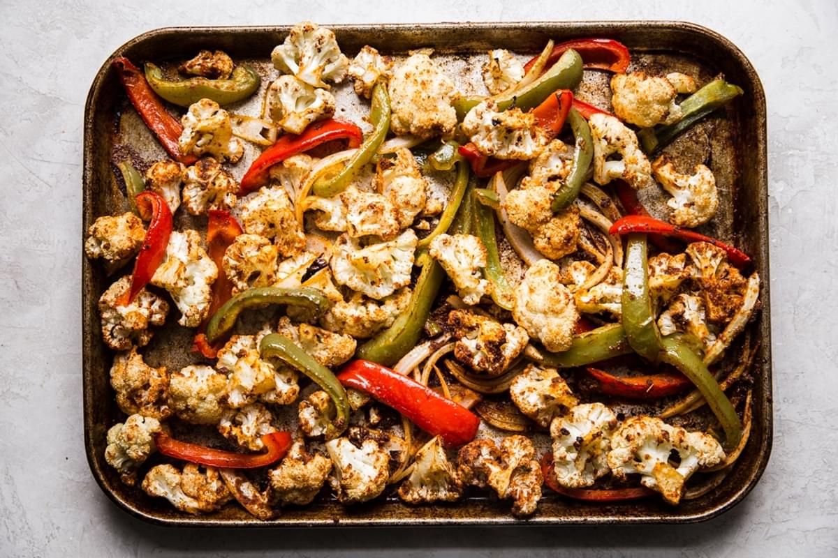 roasted cauliflower and bell peppers on a rimmed baking sheet with taco seasoning
