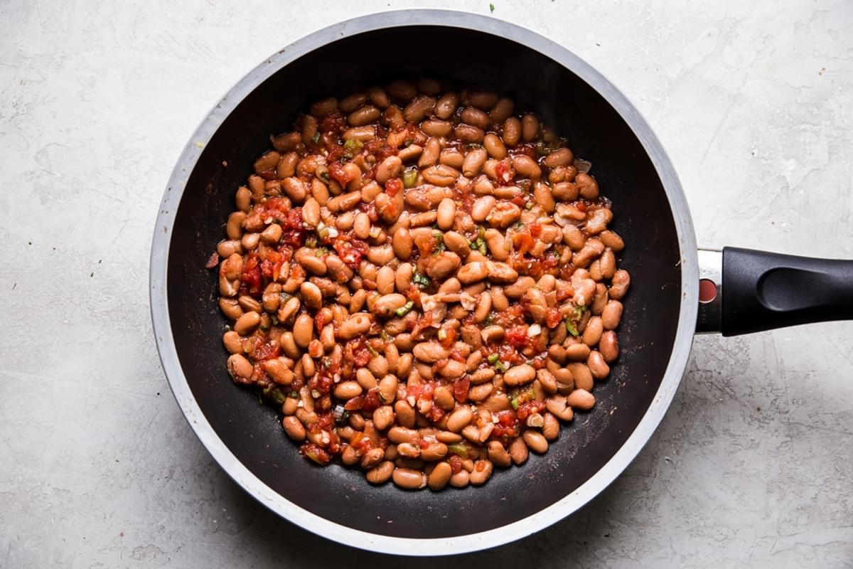 warm pinto beans simmered in a pan with salsa