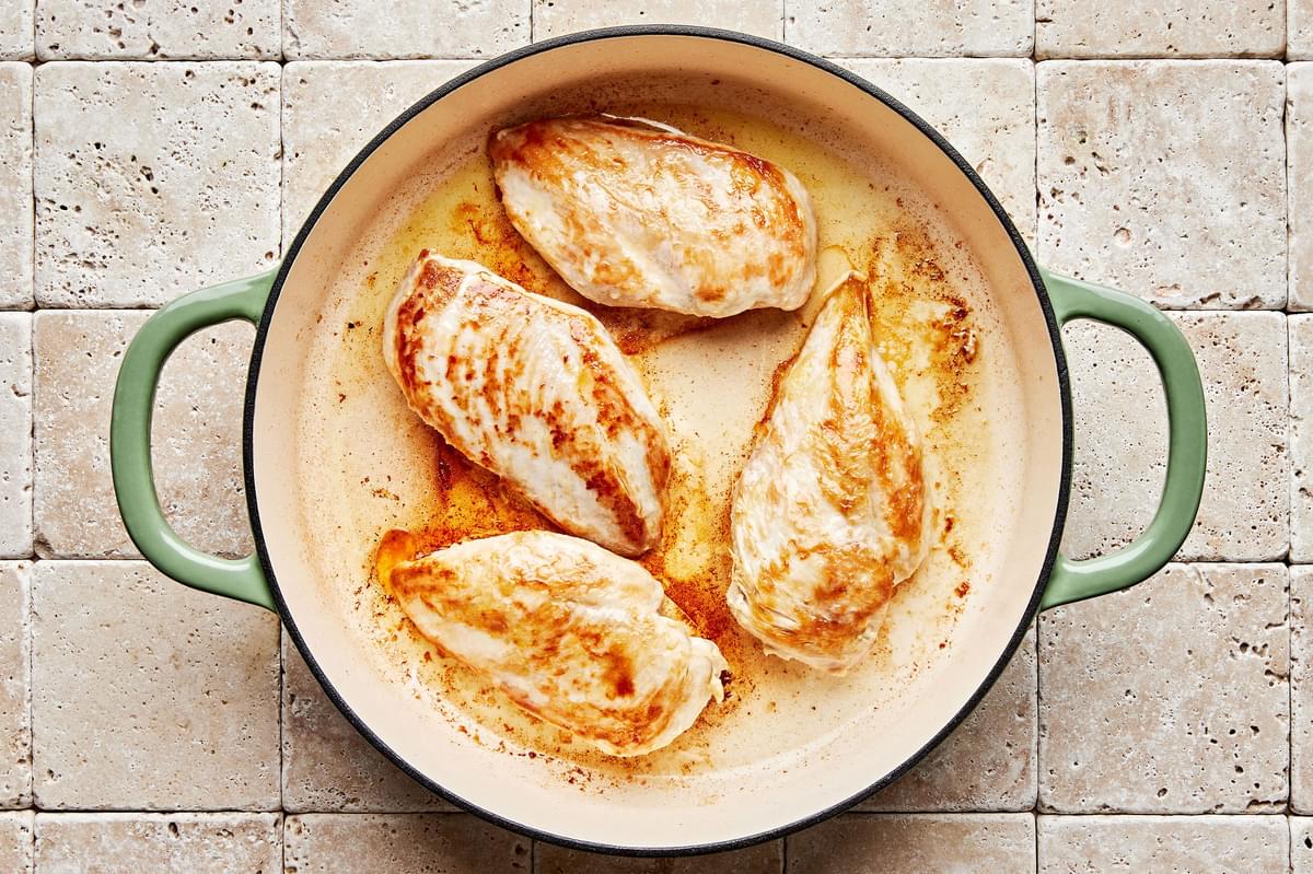 chicken being seared in olive oil in a skillet