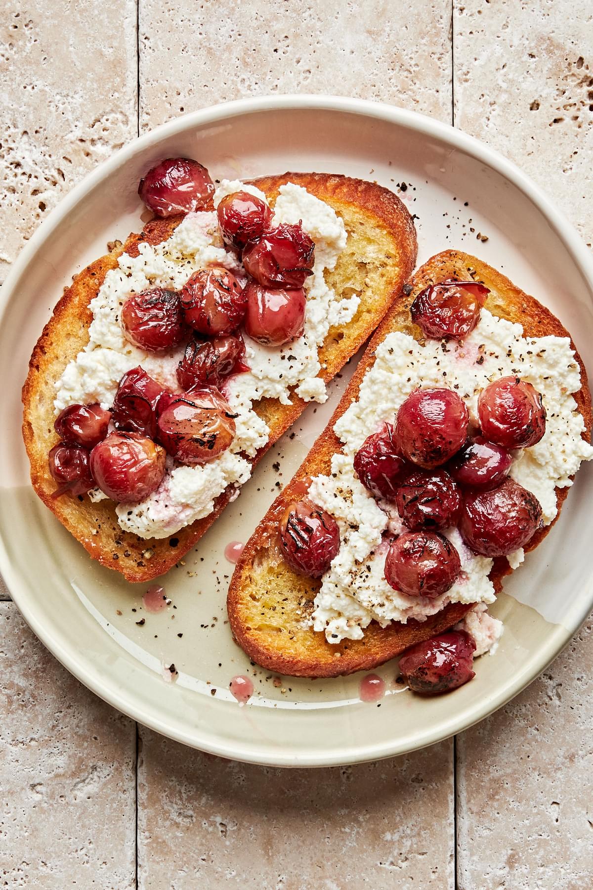 2 slices crusty bread topped with ricotta cheese and roasted red grapes