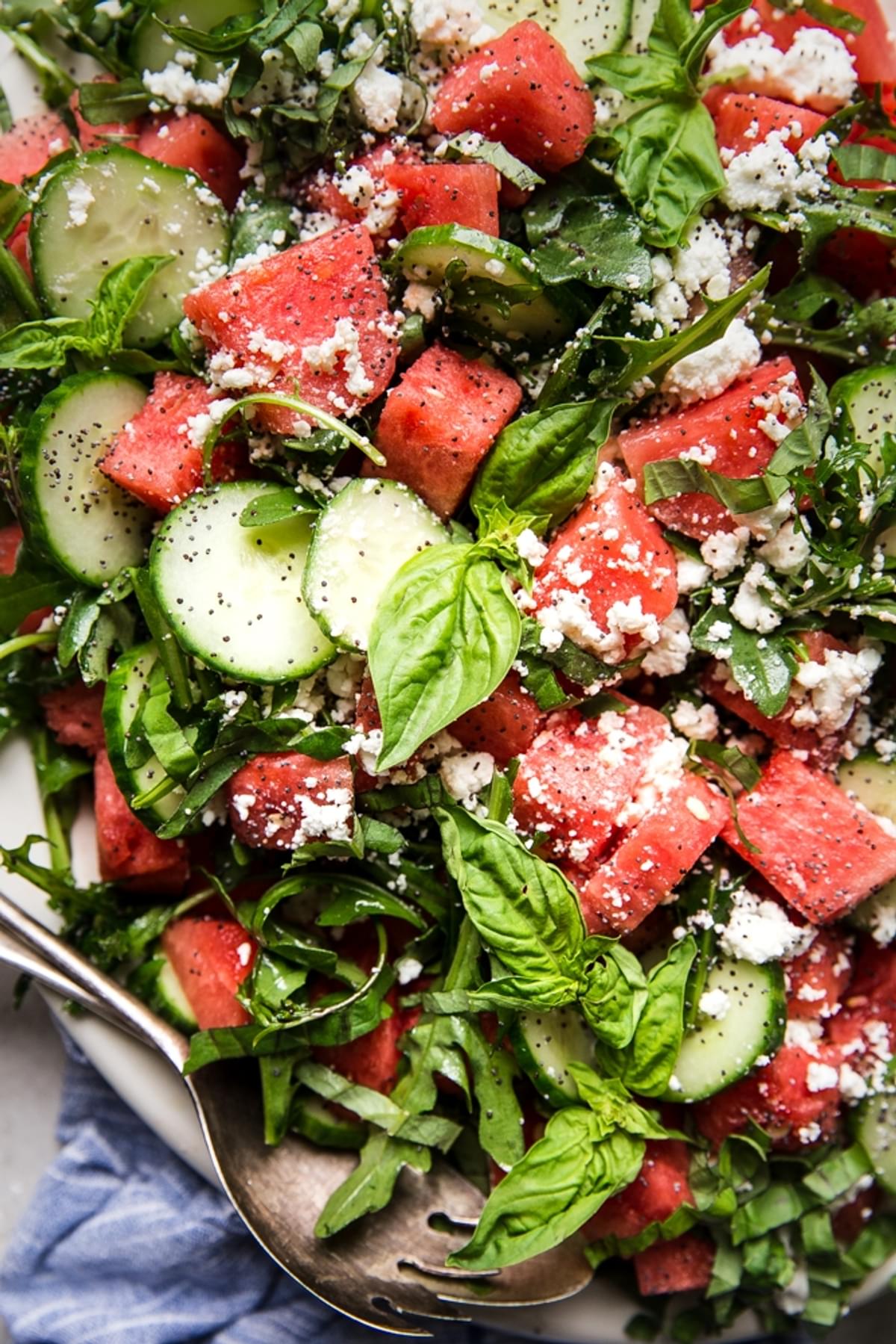 watermelon salad with cucumber, feta, basil and a poppyseed dressing on a plater
