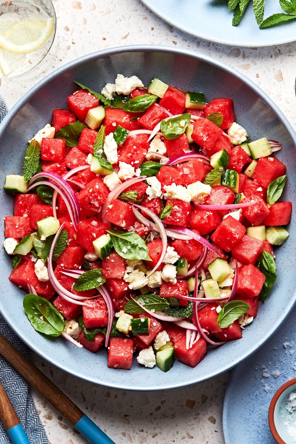 watermelon salad in a bowl made with, cucumber, red onion, feta, mint and basil