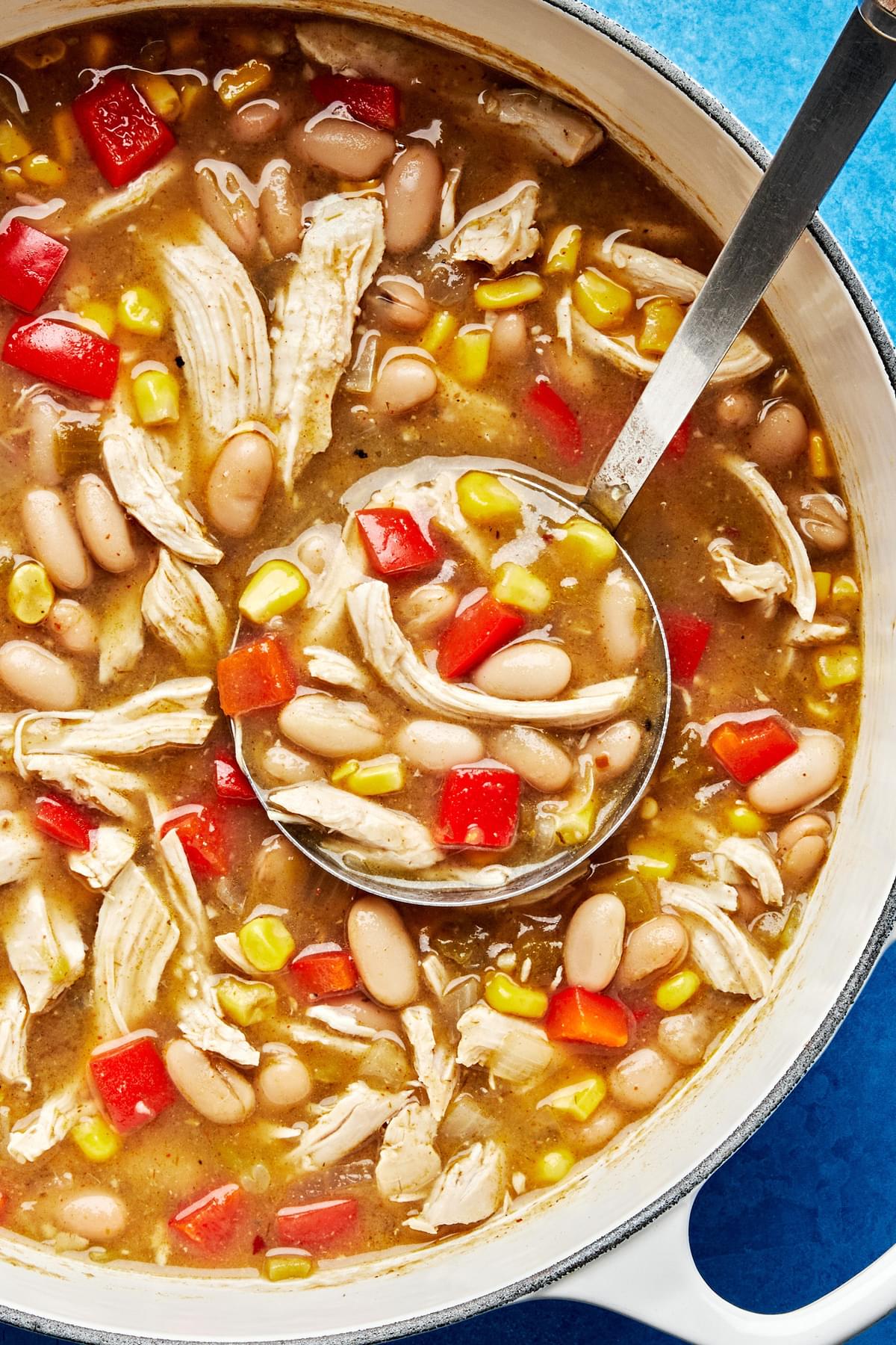 a pot of white bean chicken chili made with onion, green enchilada sauce, chiles, spices, corn and bell pepper